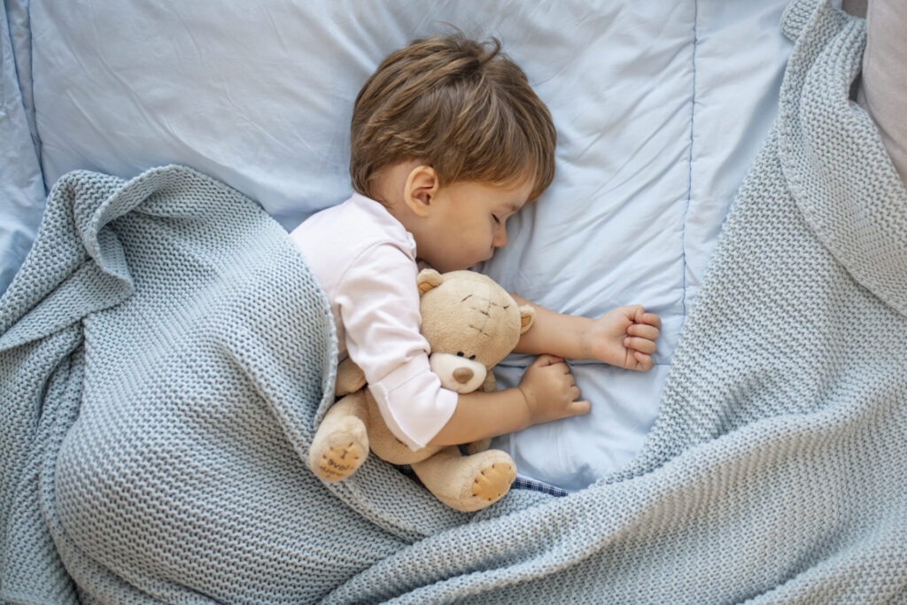 a child sleeping with a teddy bear
