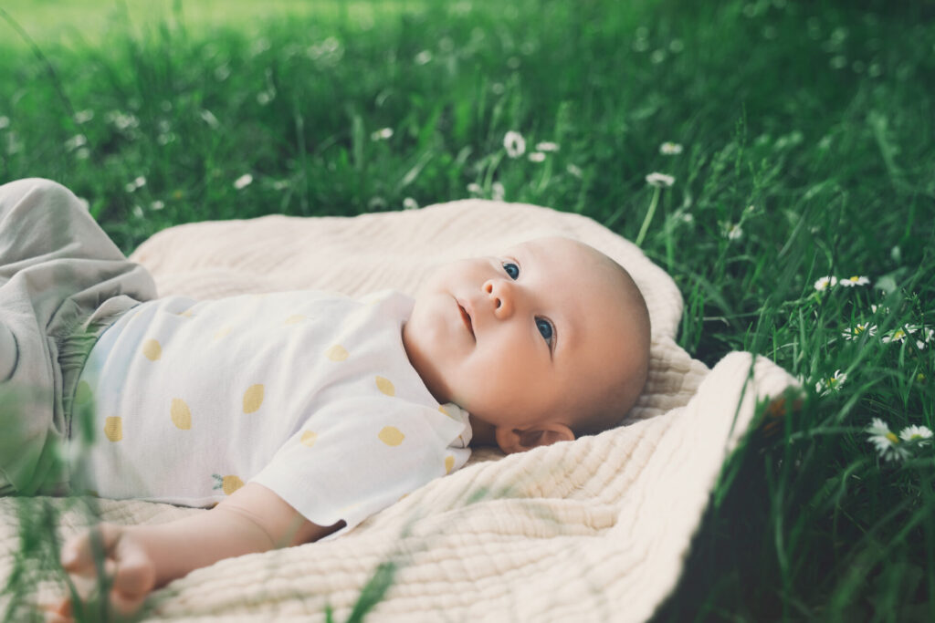 a baby lying on a blanket in grass