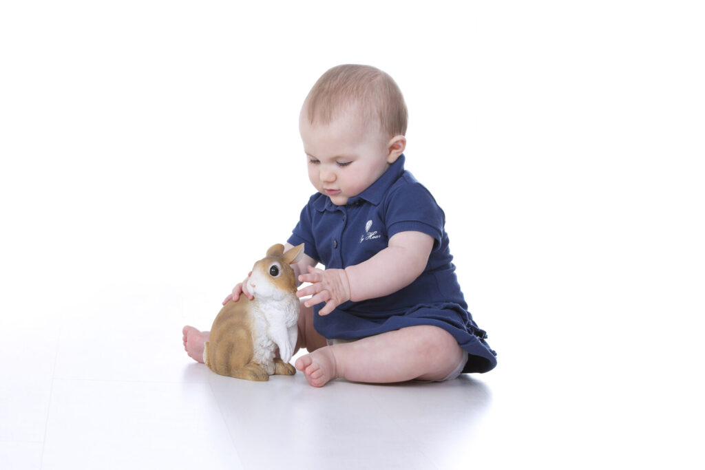 a baby playing with a toy rabbit