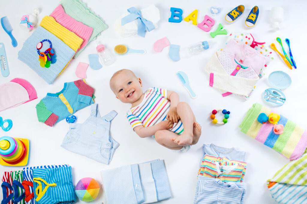 a baby lying on the floor surrounded by clothes
