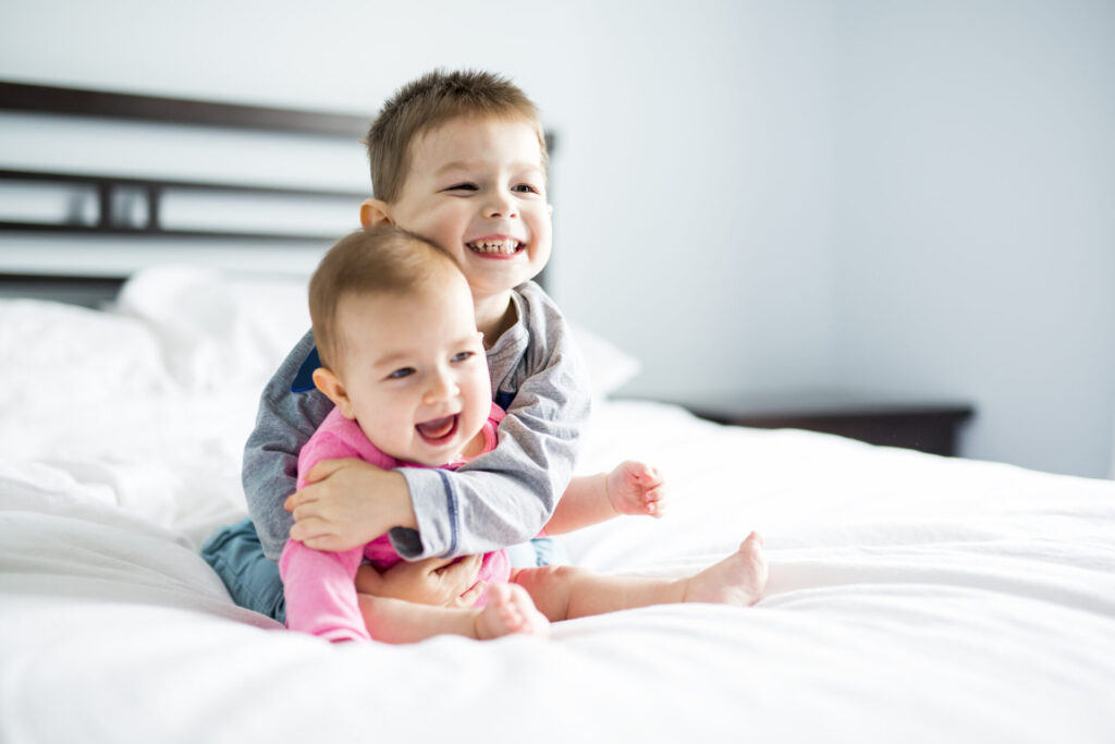 a boy hugging a baby on a bed