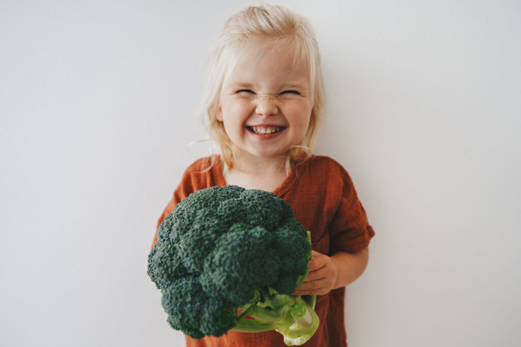 a girl holding a broccoli