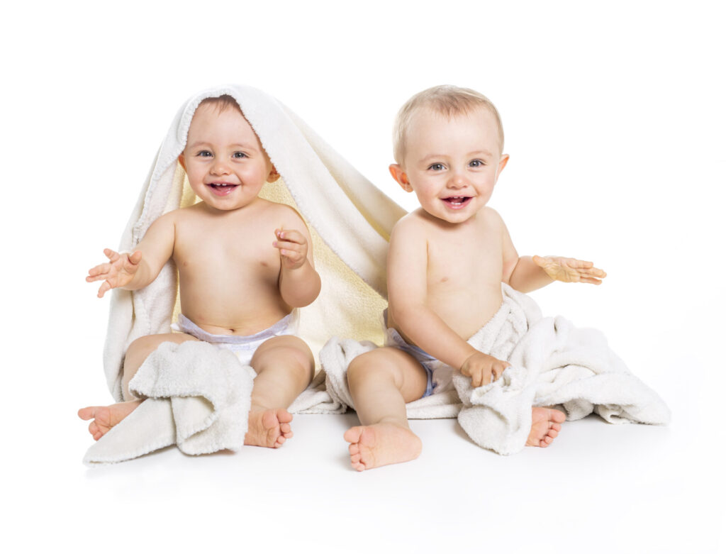two babies sitting under towels